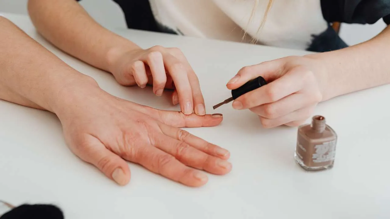 Nail technician applying polish with a fine brush.