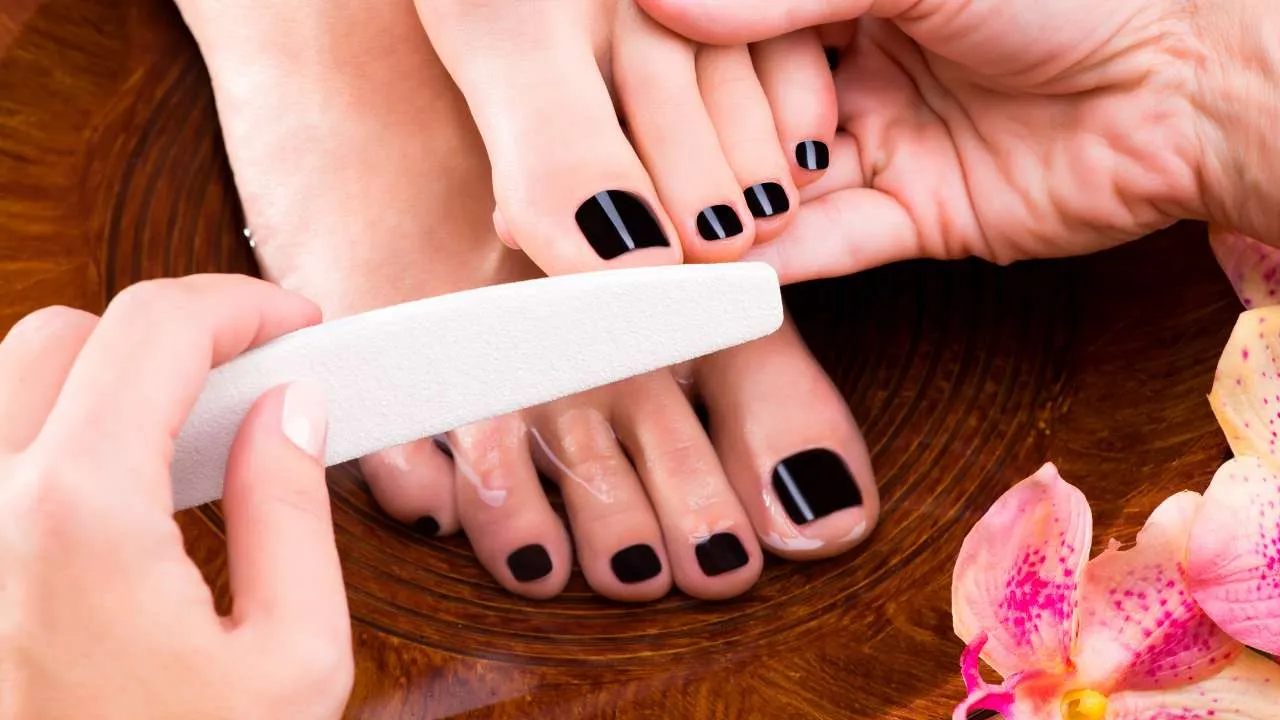 Client receiving a pedicure with pink toenails.