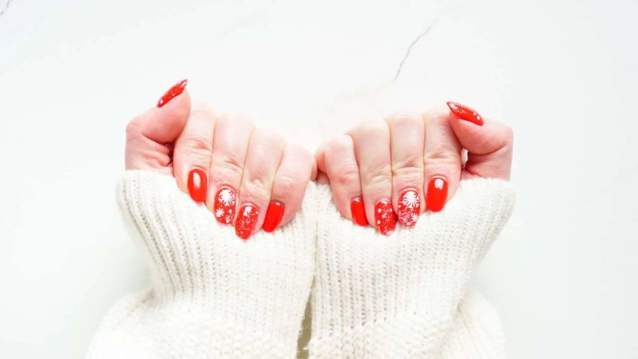 White gel nails against a pink background.