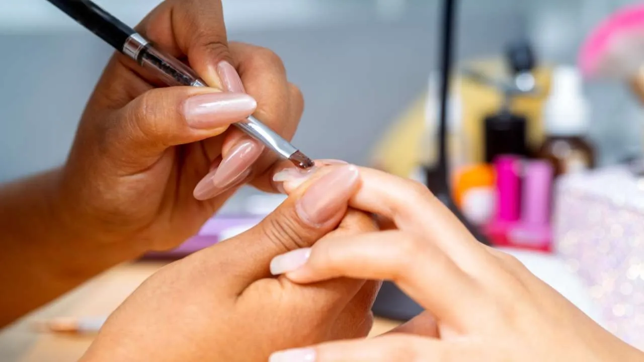 Nail technician filing gel from a client’s nail.
