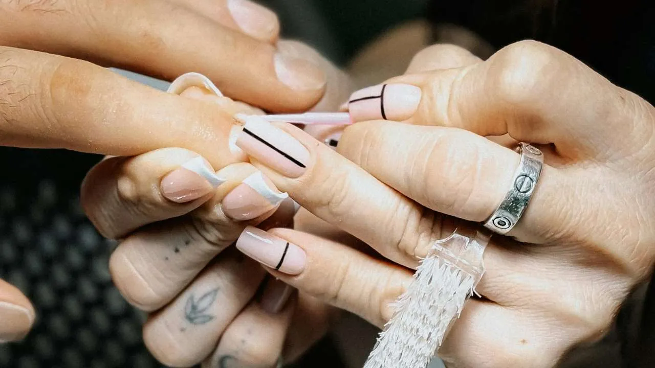 Nail technician working along a client’s nail fold.
