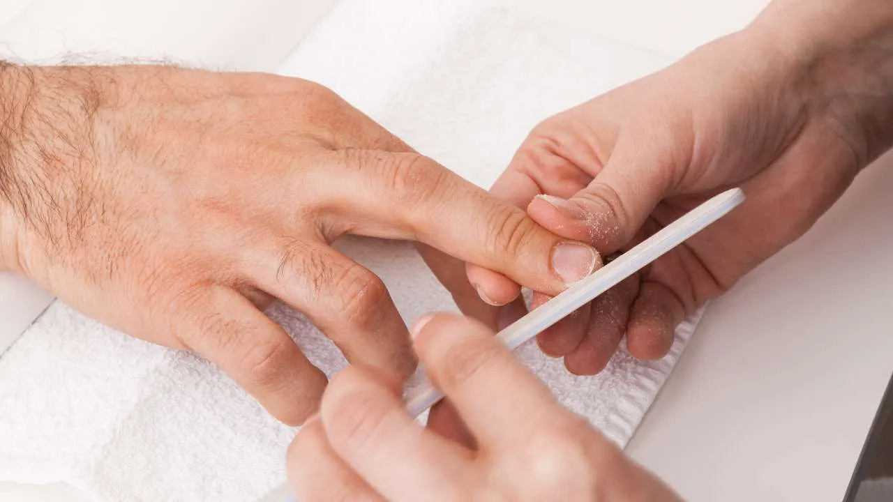 Nail technician filing a client’s natural nails.