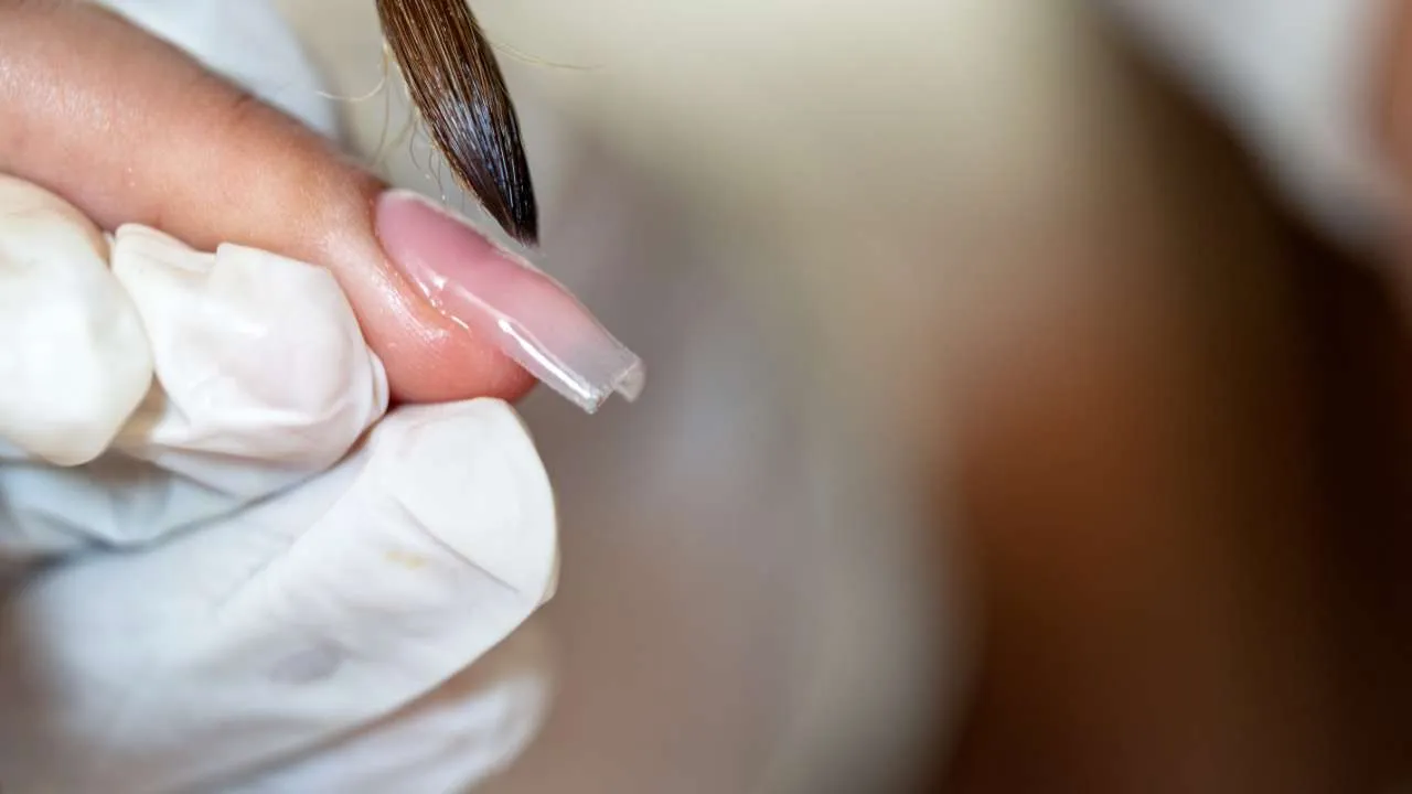 Nail technician filing a nail enhancement.