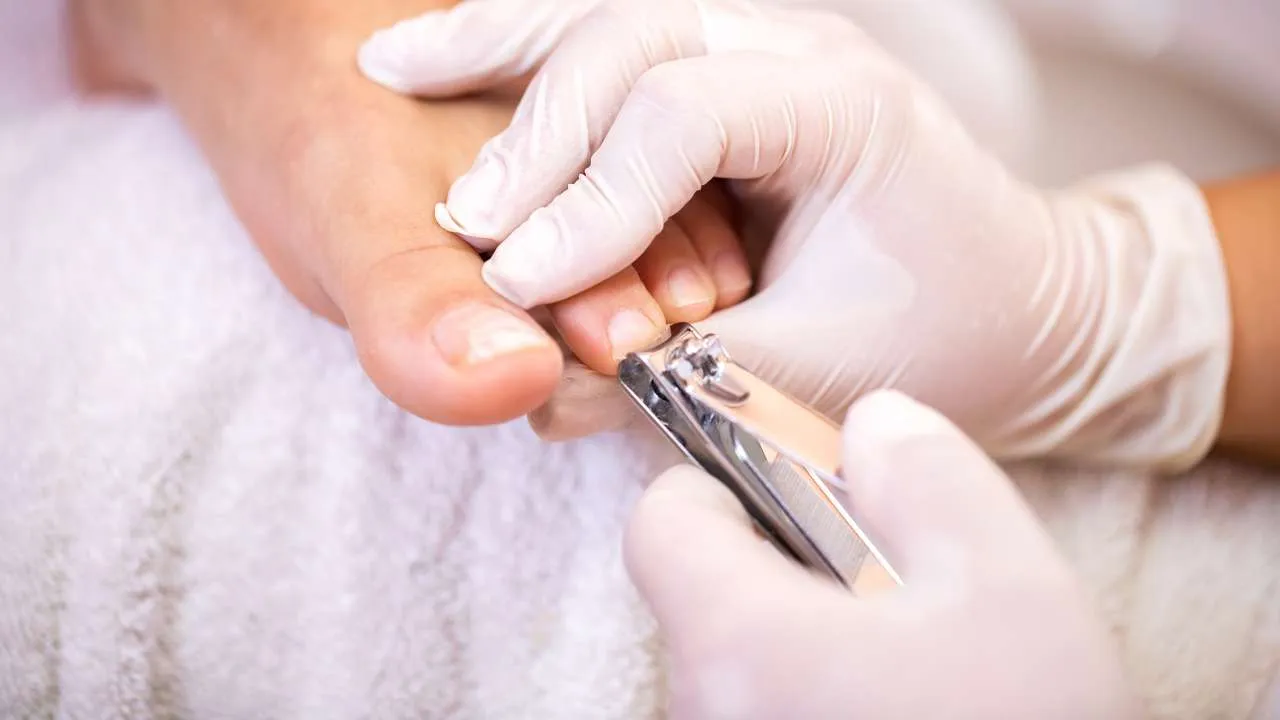 Nail technician working carefully on a toenail.