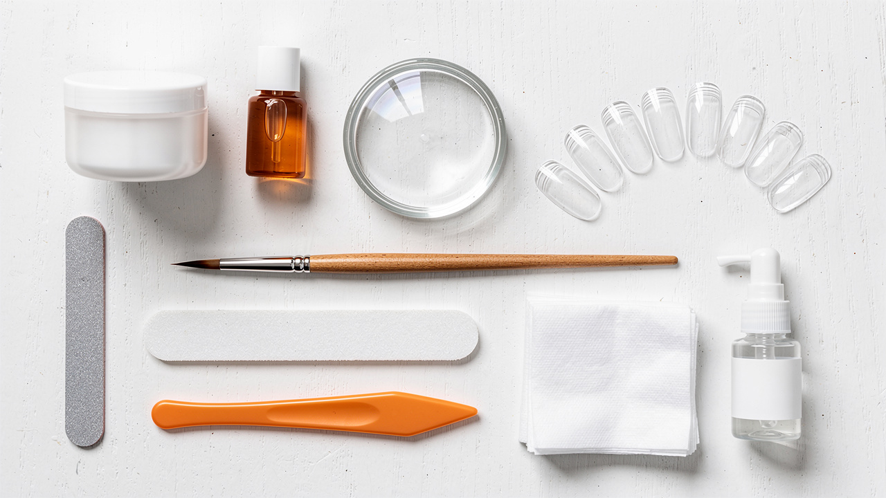 Beginner acrylic nail supplies arranged on white surface
