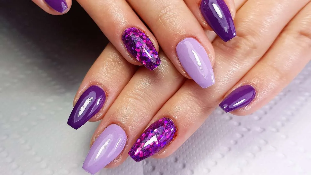 Hand with glossy purple nail polish.