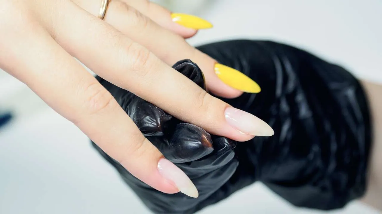 Technician filing a client’s natural nail.