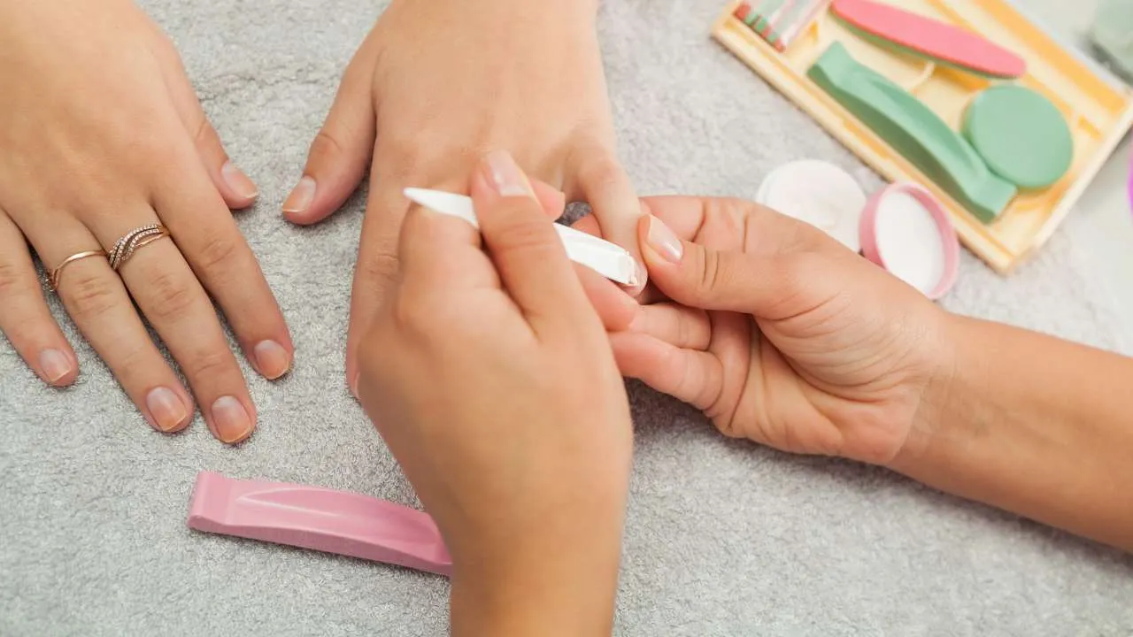 Client receiving a manicure with hands on a towel.